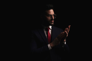handsome bearded man in elegant suit looking to side and rubbing palms