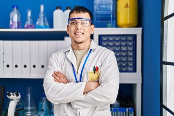 Young man scientist smiling confident standing with arms crossed gesture at laboratory