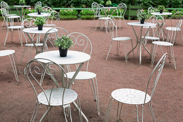 Cozy street cafe in the French style in the garden. Empty cafe terrace with white tables and chairs