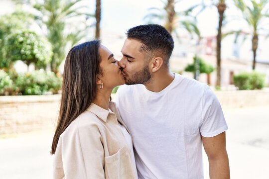 Young latin couple kissing and hugging standing at the city.