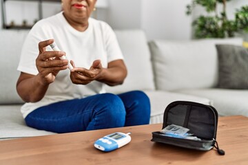 Senior african american woman smiling confident measuring glucose at home