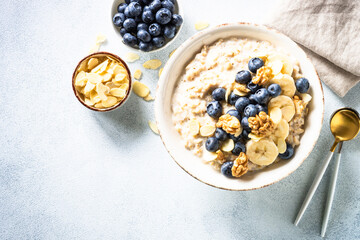 Oatmeal porrige with berries and nuts in craft bowl at white background. Top view.