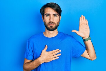 Young hispanic man wearing casual clothes swearing with hand on chest and open palm, making a...