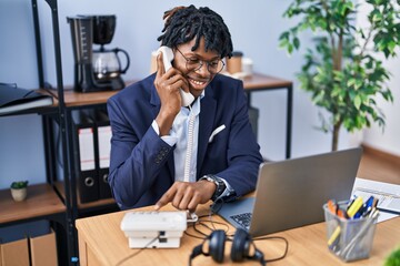 African american man business worker using laptop and talking on the telephone at office