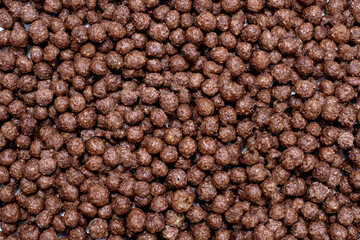 Background of round chocolate flakes in the form of balls. The concept of fast carbohydrate breakfast. Free space for text and advertising. American style chocolate balls background