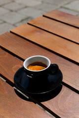 Cup of hot and creamy Italian espresso on wooden table. coffee break on sunny day