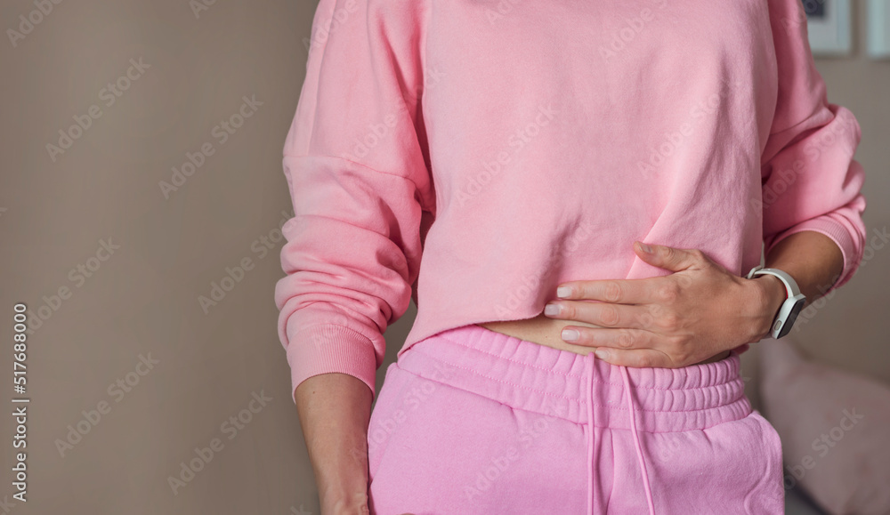 Wall mural Unrecognized woman standing  and holding her hands on her belly . Woman suffering from abdominal pain