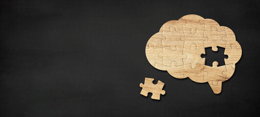 Brain shaped wooden jigsaw puzzle on black background, a missing piece of the brain puzzle, mental health and problems with memory