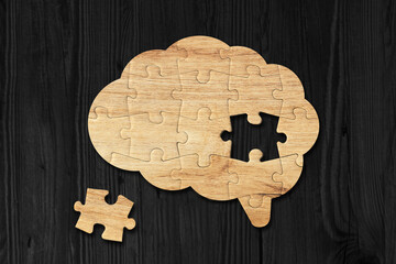 Brain shaped wooden jigsaw puzzle on black background, a missing piece of the brain puzzle, mental...