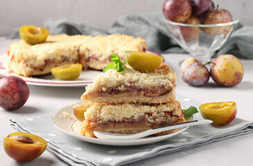 Homemade shortbread plum pie with cut pieces on plate on light gray background, Closeup