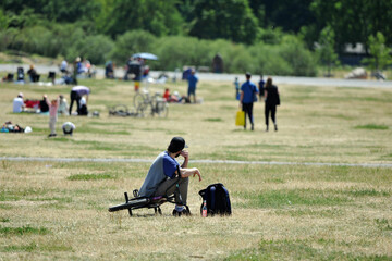 A man rests on his bicycle on a green meadow while he watches other people. A warm and sunny day on...