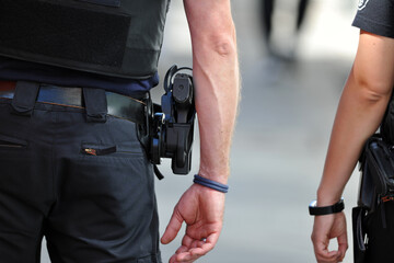 Partial view of a male and a female police officer walking on patrol in Berlin-City on a warm and...