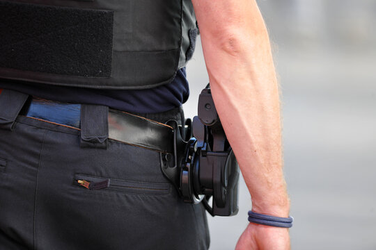Partial view of a male police officer walking on patrol in Berlin-City on a warm and sunny summer day. A right hand over a pistol. 