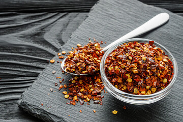 spicy chili flakes on a dark stone background