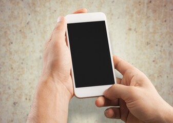 A hand hold phone against a light stone wall.