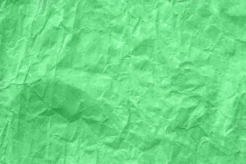 High detail of the abstract texture of the packaging paper. The texture of crumpled green craft paper. Crumpled green paper background top view. The texture of crumpled green paper. Space for text.