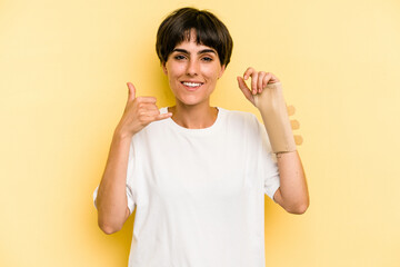 Young caucasian woman hand sling isolated on yellow background showing a mobile phone call gesture...
