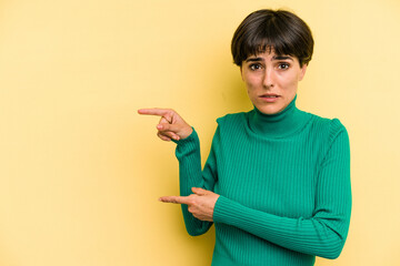 Young caucasian woman with a short hair cut isolated shocked pointing with index fingers to a copy space.