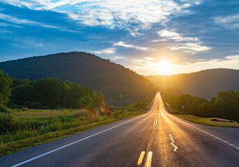 Summer road trip with setting sun in mountain scenery 
