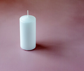 A white tall candle on the pink background with copy space
