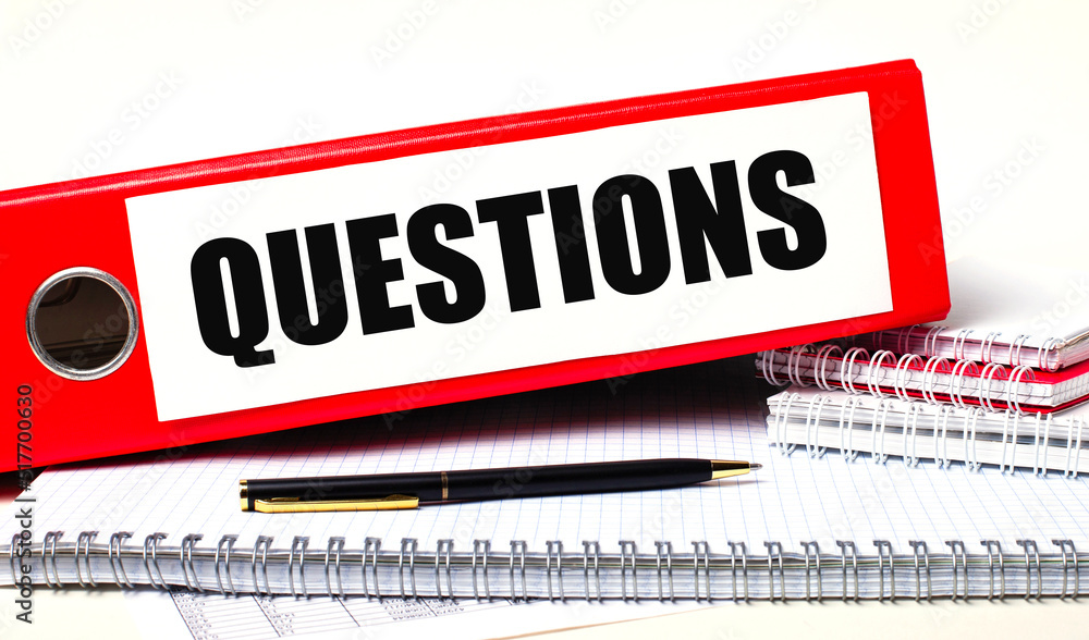 Poster on the desktop are notebooks, a pen and a red folder for papers with the text questions. business co