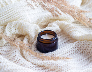 Soy wax candle in amber glass with dried flowers.