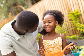 Image of happy african american father and daughter gardening together
