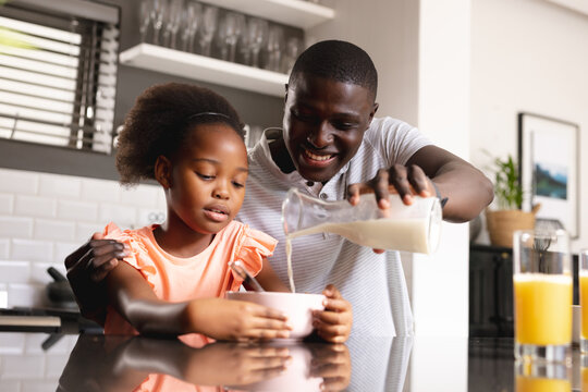 Image of african american father and daughter preparing breakfast in kitchen