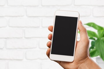A hand hold phone against a light stone wall.