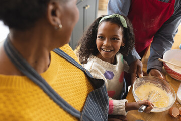 Image of happy african american grandparents and granddaughter baking in kitchen