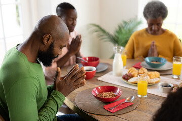 Image of happy multi generation african american family praying before breakfast