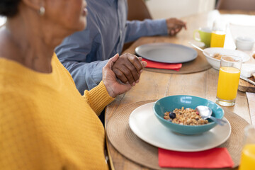 Image of hands of african american family praying before meal