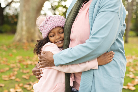 Image of happy african american grandmother and granddaughter embracing in garden