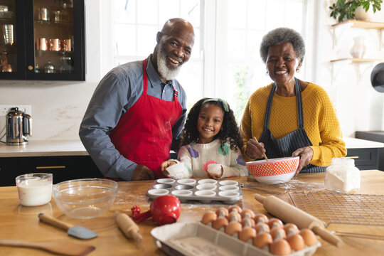 Image of happy african american grandparents and granddaughter baking in kitchen