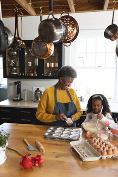 Vertical Image Of Happy African American Grandmother And Granddaughter Baking In Kitchen