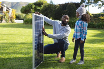 Image of happy african american father showing solar panels to daughter - Powered by Adobe