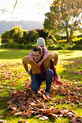Vertical image of happy caucasian father and daughter in autumn garden