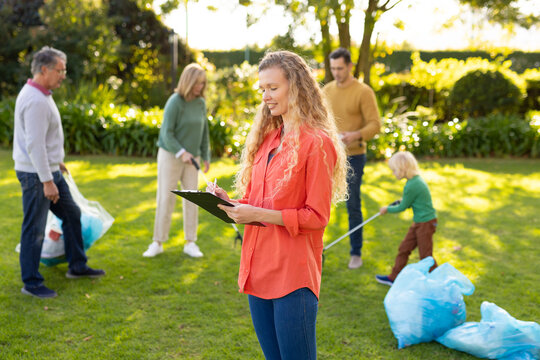 Image of happy multi generation caucasian family collecting waste in garden