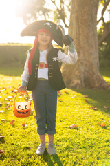 Vertical image of happy caucasian boy in pirate costume in autumn garden