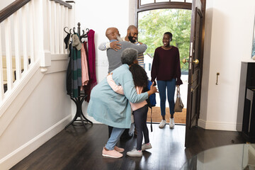 Image of happy multi generation african american family entering house and welcoming each other - obrazy, fototapety, plakaty
