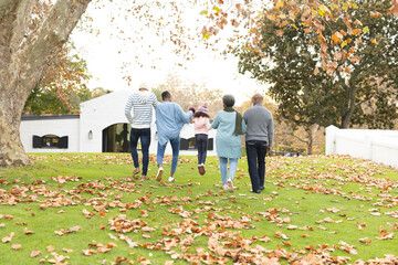 Fototapeta premium Image of back view of multi generation african american family having fun outdoors in autumn