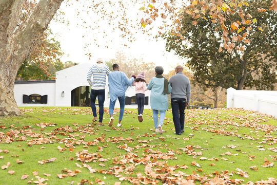 Image of back view of multi generation african american family having fun outdoors in autumn