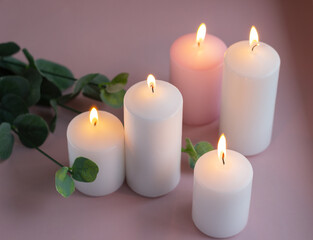 Obraz na płótnie Canvas Set of white and pink burning wax candles with green leaves