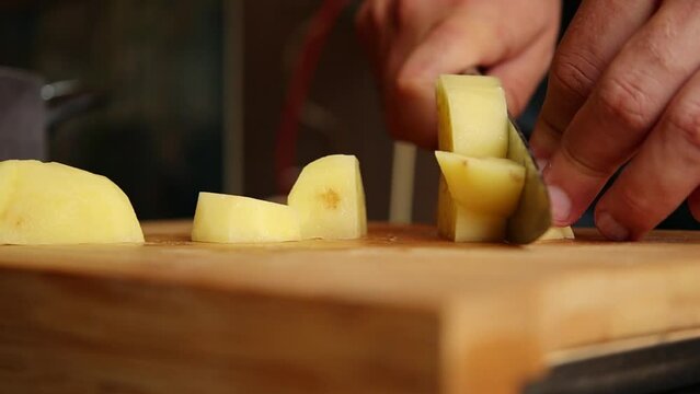man hands cutting peeled potatoes close up on wooden board