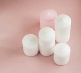 Set of white and pink wax candles on the pink background