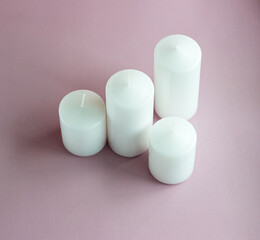 Set of white wax candles on the pink background