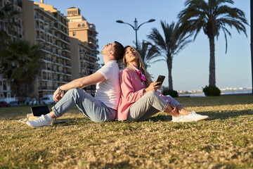 Naklejka na ściany i meble Couple using mobile in grass together