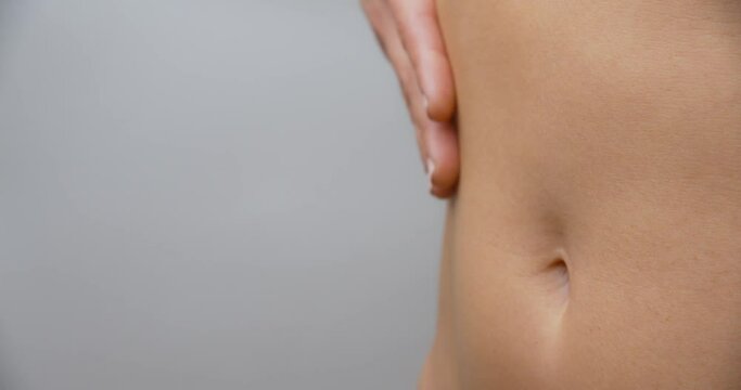 Woman touching her abdomen and caressing her skin.
Isolated shot.