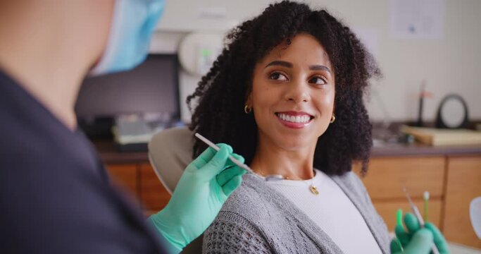 Woman talking to dentist during an appointment. Happy female patient with beautiful teeth and a bright smile in an oral checkup. Getting a cleaning and tooth whitening treatment for dental healthcare