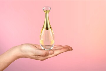 Perfume and toilet water. A woman's hand elegantly holds a glass perfume bottle. The concept of perfumery and beauty.